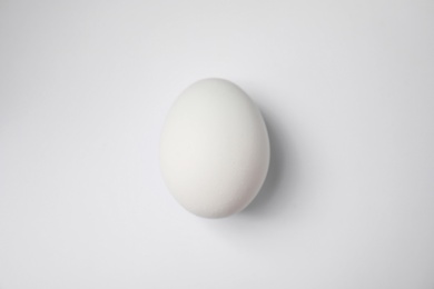 Photo of Raw chicken egg on white background, top view