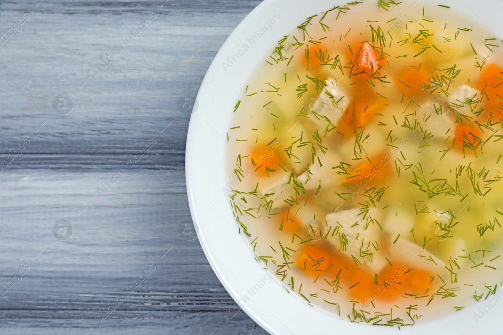 Photo of Bowl of fresh homemade soup to cure flu on wooden background, top view with space for text