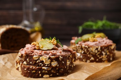 Photo of Delicious liverwurst sandwiches with pickled cucumber and mustard on wooden board, closeup