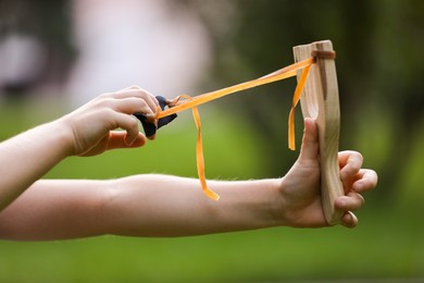 Photo of Little girl playing with slingshot outdoors, closeup