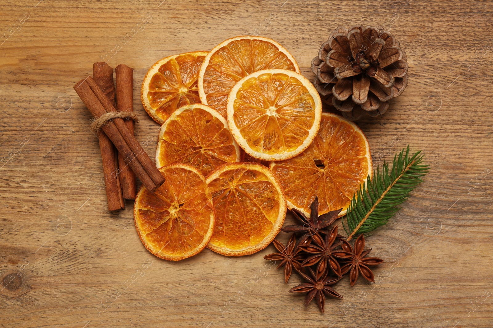 Photo of Dry orange slices, cinnamon sticks, fir branch and anise stars on wooden table, flat lay