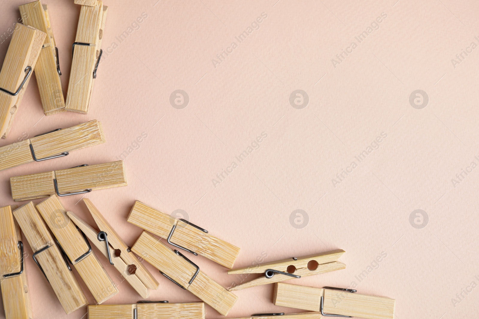 Photo of Many wooden clothespins on light pink background, flat lay. Space for text