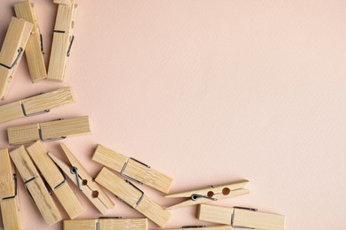 Many wooden clothespins on light pink background, flat lay. Space for text