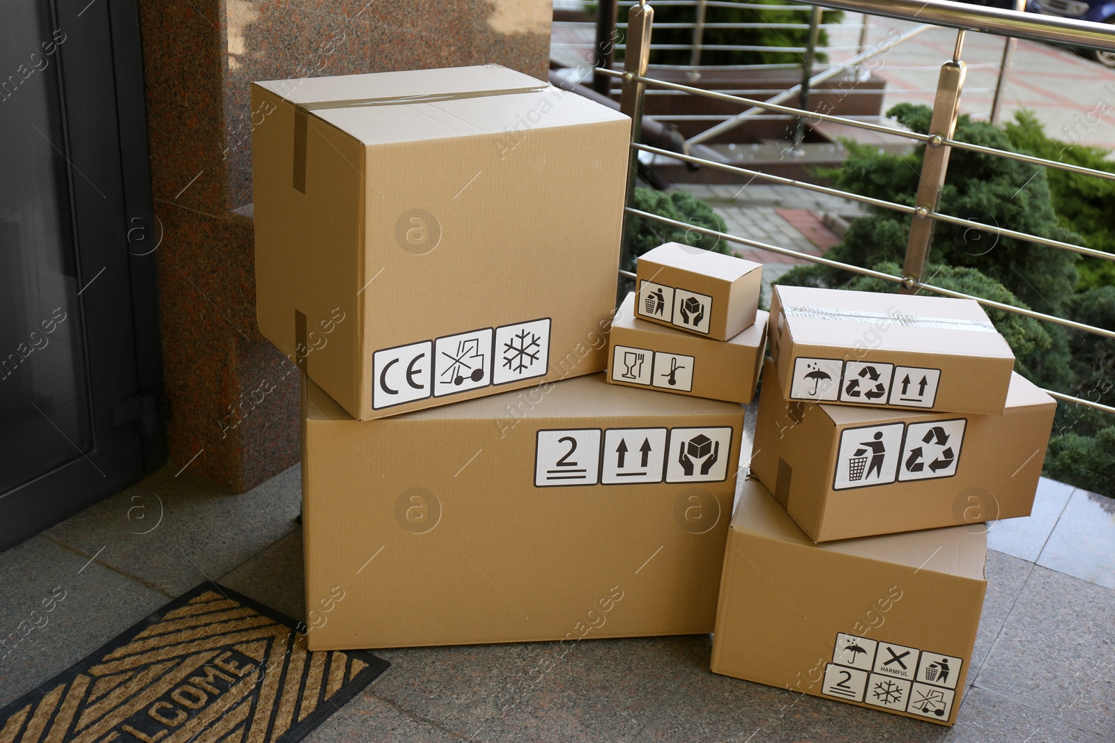 Photo of Cardboard boxes with different packaging symbols on porch near entrance. Parcel delivery