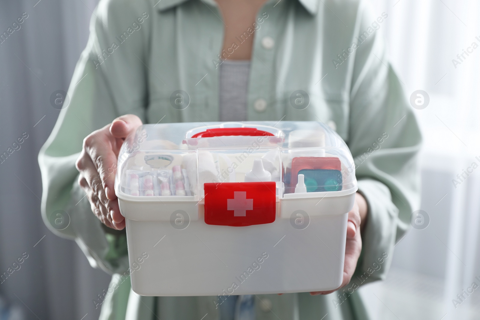 Photo of Woman holding first aid kit indoors, closeup