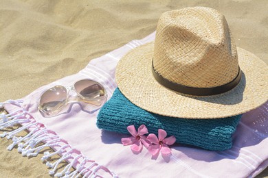 Stylish beach accessories and flowers on sand outdoors