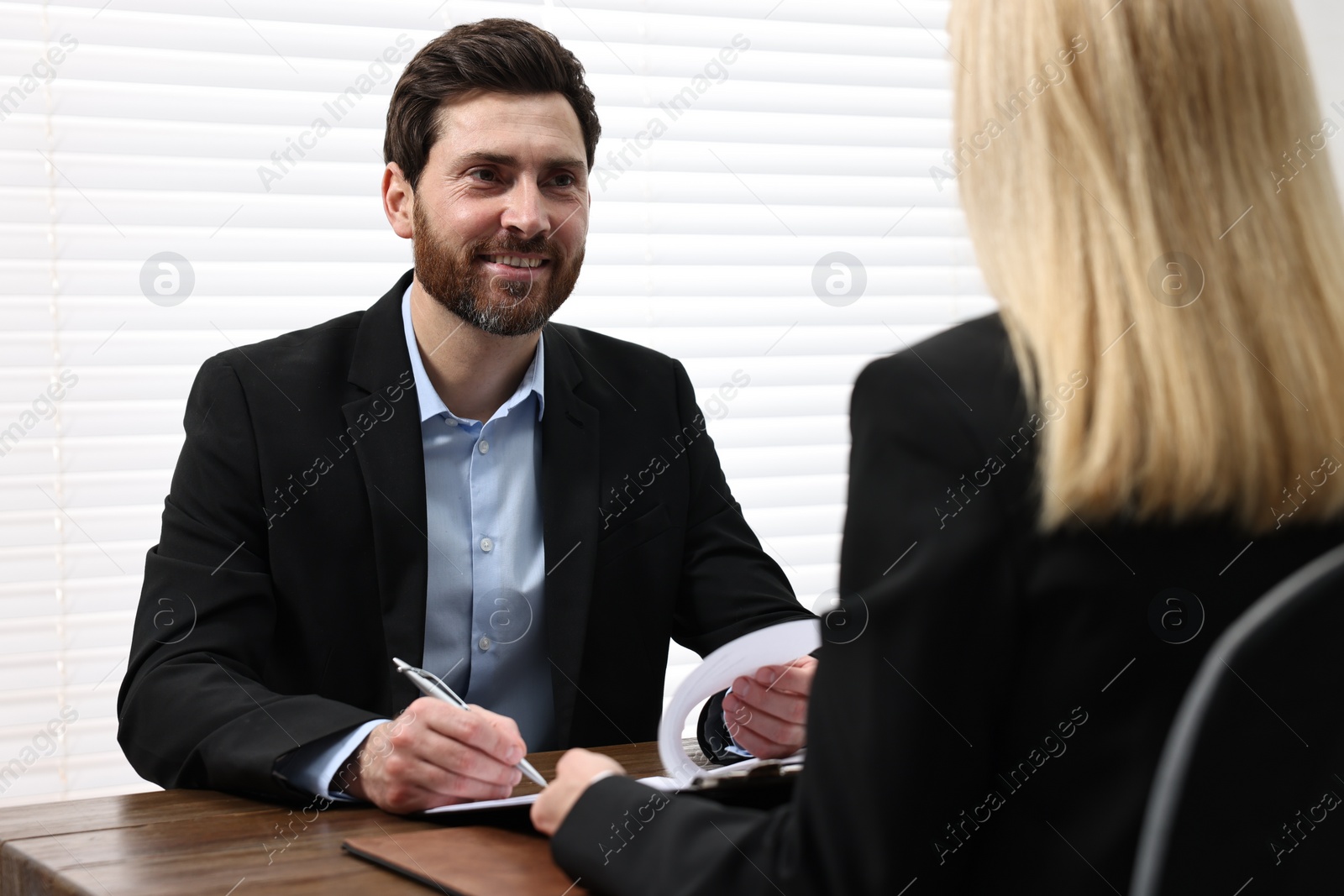 Photo of Man signing document at table in lawyer's office
