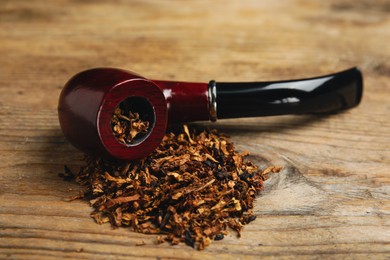 Photo of Smoking pipe with tobacco on wooden table