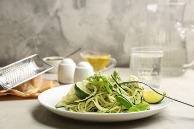Photo of Delicious zucchini pasta with lime, grated cheese and basil on light table