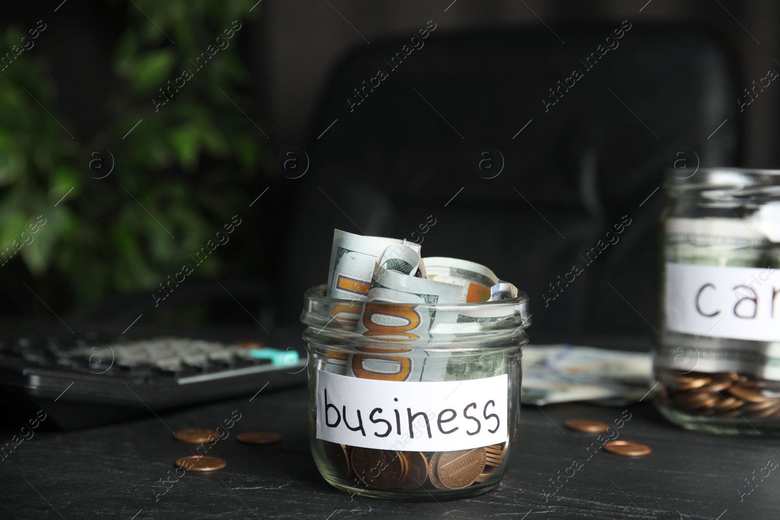 Photo of Glass jar with money and tag BUSINESS on black table