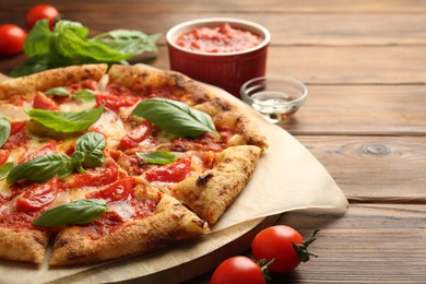 Delicious Margherita pizza and ingredients on wooden table, closeup