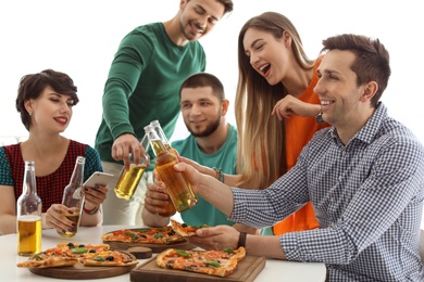 Young people having fun party with delicious pizza indoors