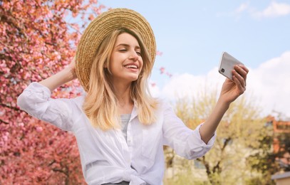 Photo of Happy woman taking selfie outdoors on spring day