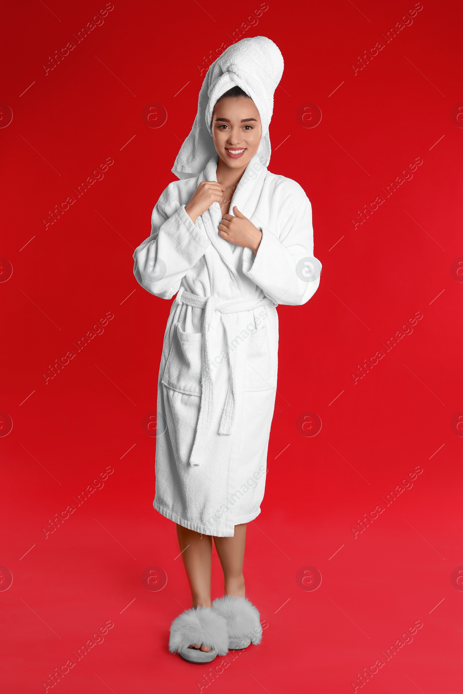 Photo of Beautiful young woman in bathrobe on red background