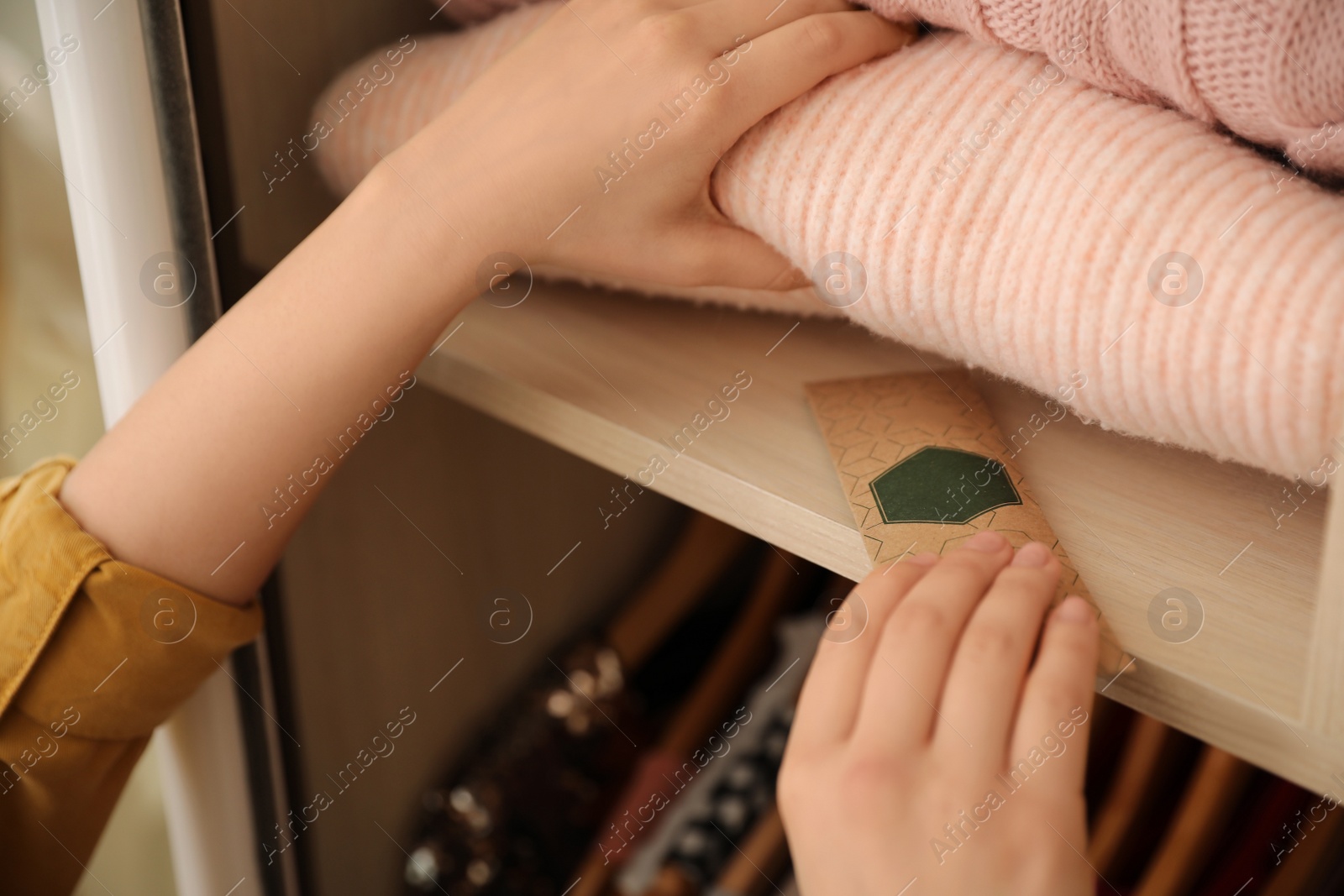 Photo of Woman putting scented sachet in wardrobe, closeup