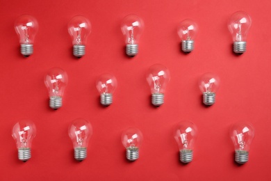 Photo of New incandescent lamp bulbs on red background, flat lay