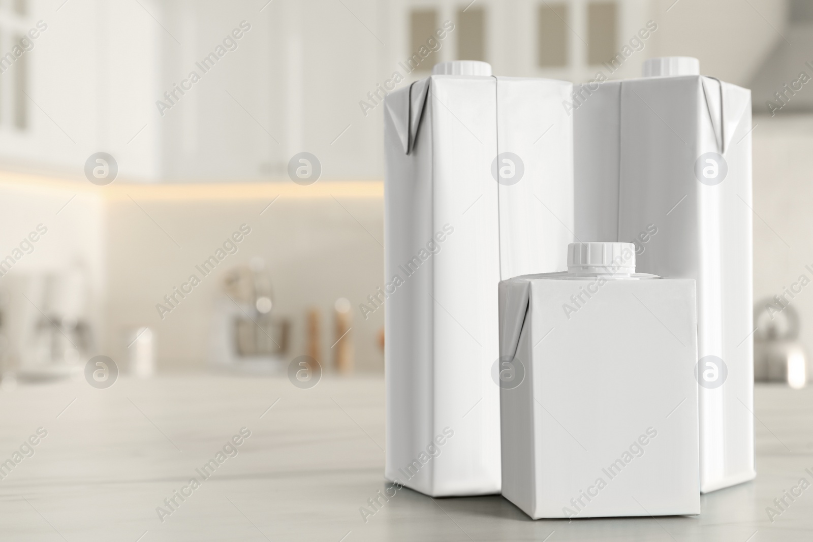 Photo of Carton boxes of milk on table in kitchen, space for text