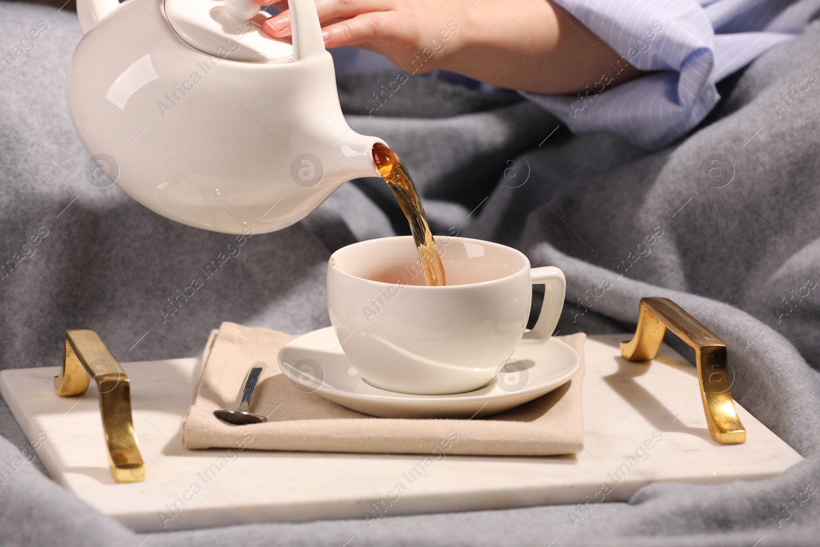 Photo of Woman pouring aromatic tea into cup at table, closeup