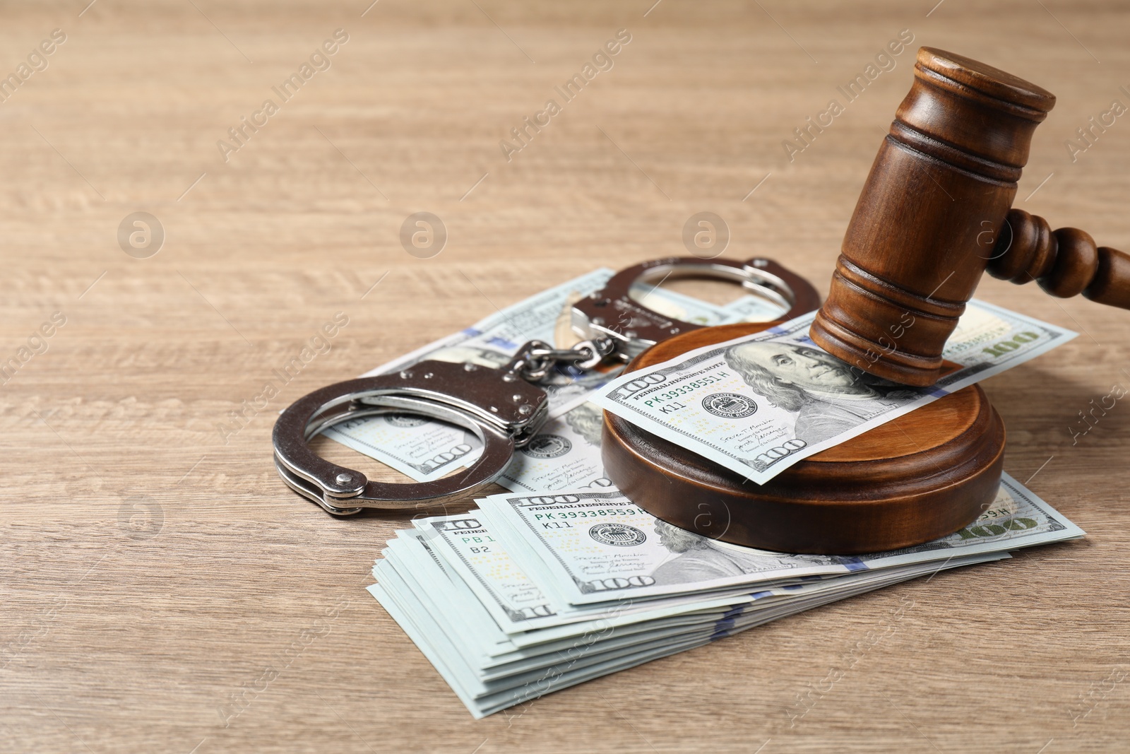 Photo of Judge's gavel, money and handcuffs on wooden table