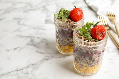 Photo of Healthy quinoa salad with vegetables in jars on table. Space for text