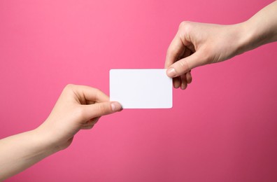 Photo of Women holding blank gift card on pink background, closeup