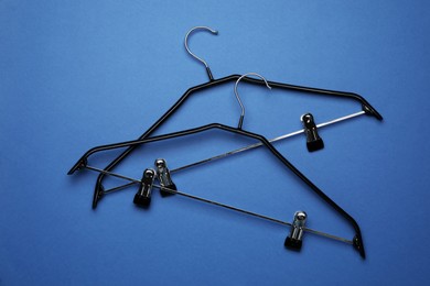 Empty clothes hangers on blue background, flat lay