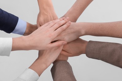Photo of Women holding hands together on light background, closeup