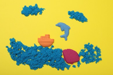 Photo of Sea inhabitants made of kinetic sand on yellow background, flat lay