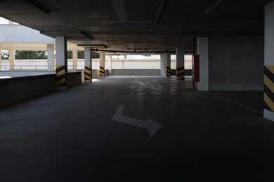 Empty open car parking garage with warning stripes on columns