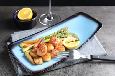 Photo of Delicious fried scallops with asparagus served on grey table