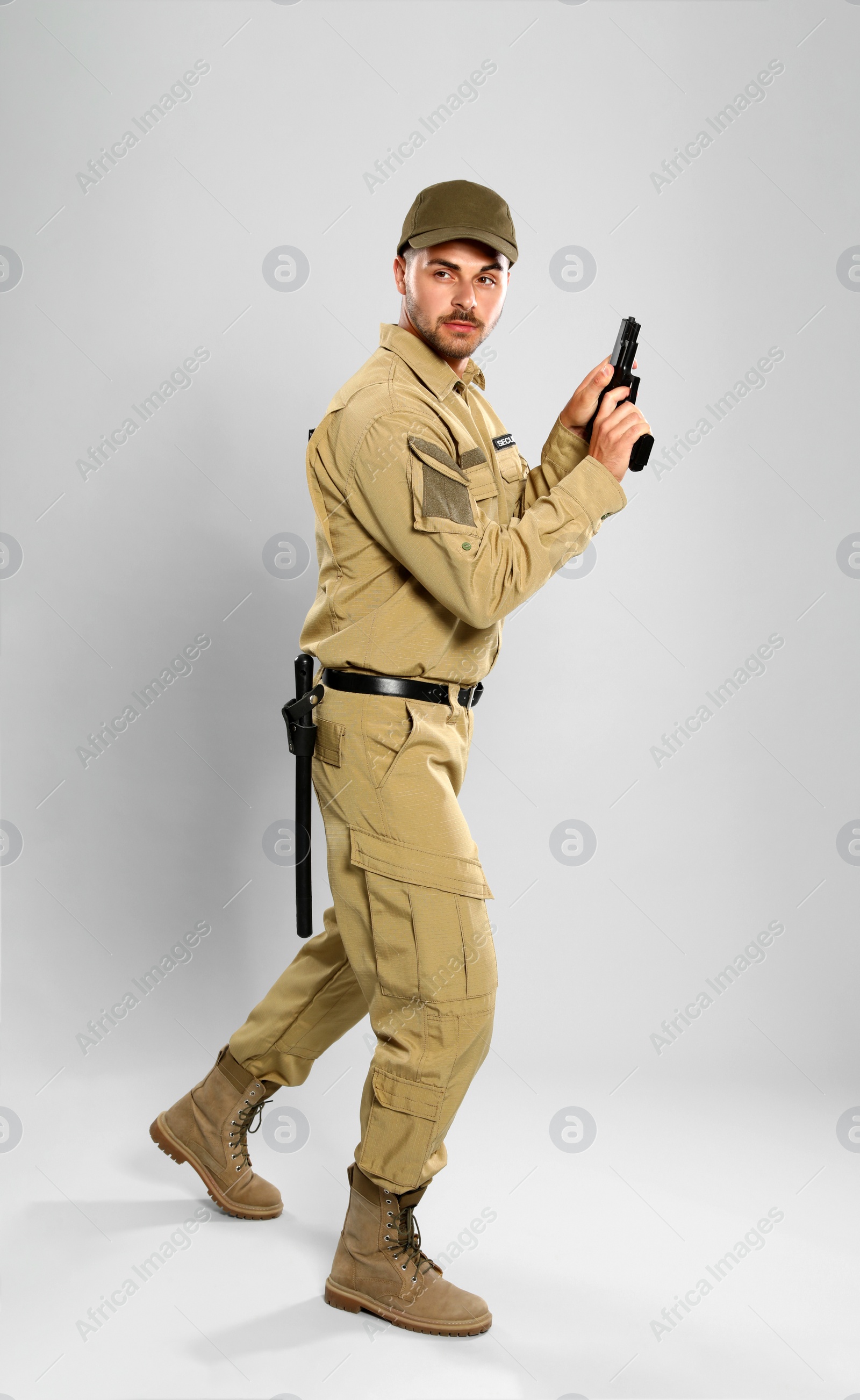 Photo of Male security guard in uniform with gun on grey background