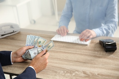 Man with money at cash department window, closeup