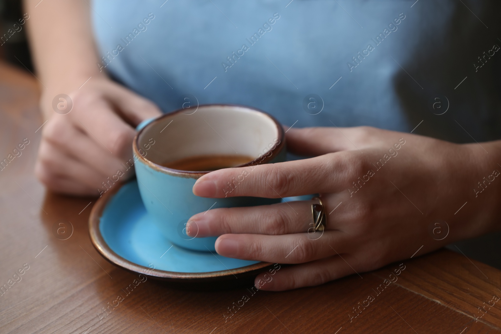 Photo of Woman with cup of fresh aromatic coffee at table, closeup