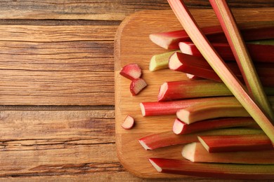 Many cut rhubarb stalks on wooden table, top view. Space for text