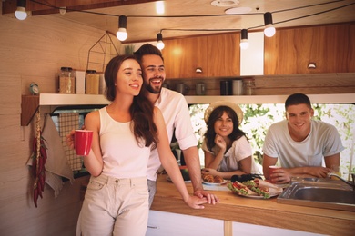 Happy young people having breakfast in trailer. Camping vacation