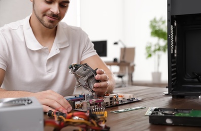 Photo of Male technician repairing computer at table indoors