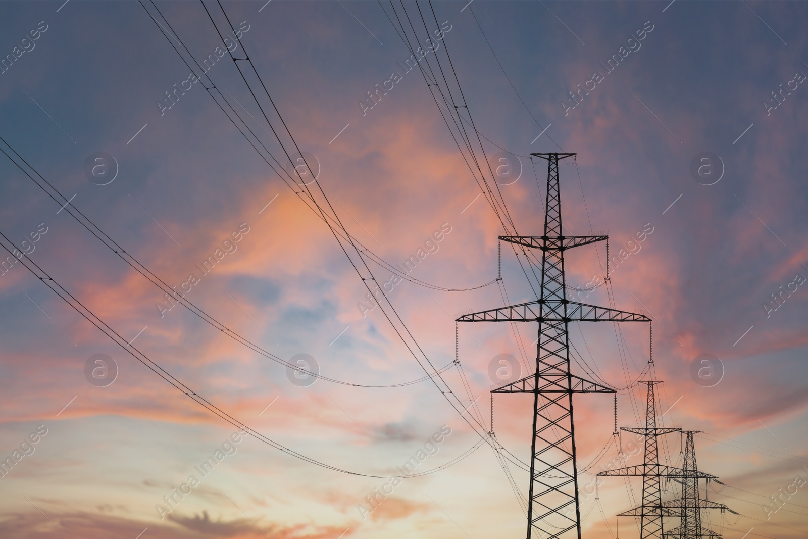 Photo of Telephone poles with cables at sunset outdoors