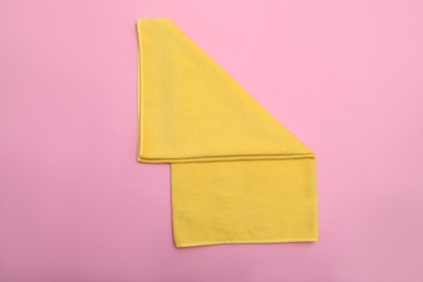 Photo of Folded yellow beach towel on pink background, top view