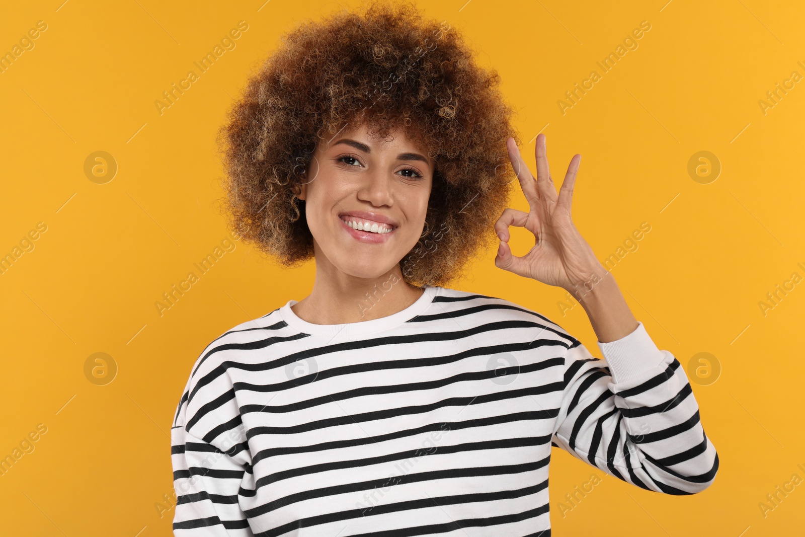 Photo of Woman with clean teeth showing OK gesture on yellow background