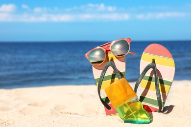 Photo of Composition with beach accessories on sand near sea in summer. Space for text