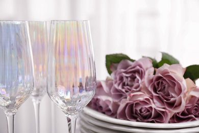 Set of glasses and dishes with flowers on light background, closeup