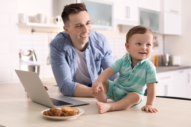 Photo of Young father with his cute little son in kitchen