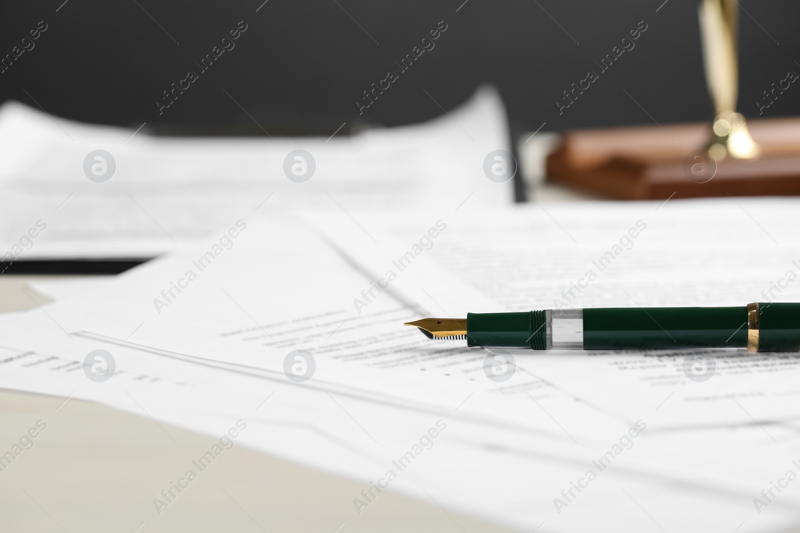 Photo of Signing notary document with fountain pen at light table, closeup. Space for text