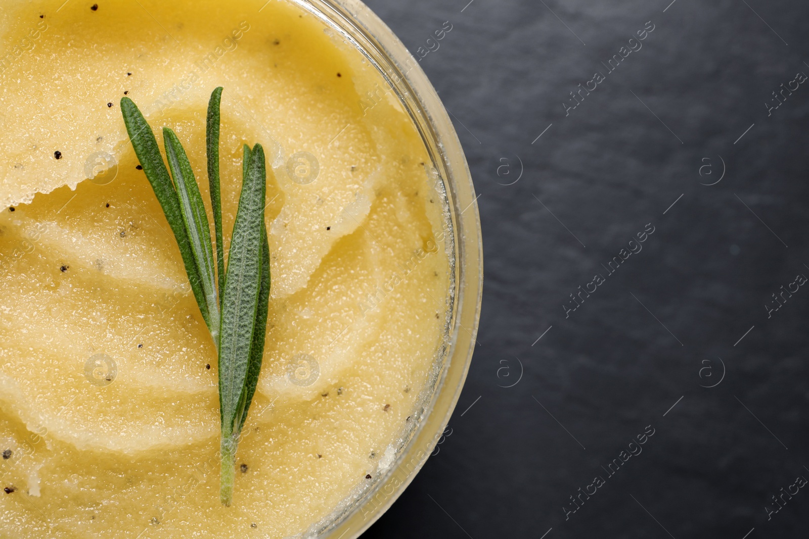 Photo of Body scrub and rosemary in jar on black table, top view. Space for text