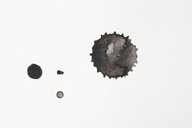 Photo of Blots of black ink on white background, flat lay