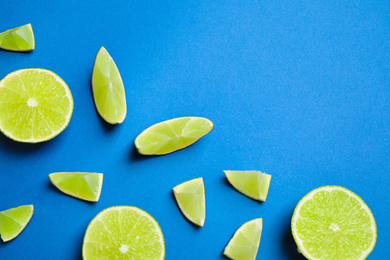 Juicy fresh lime slices on blue background, flat lay. Space for text