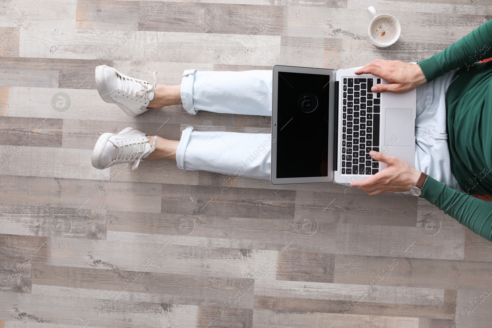 Photo of Young man with laptop sitting on floor, top view