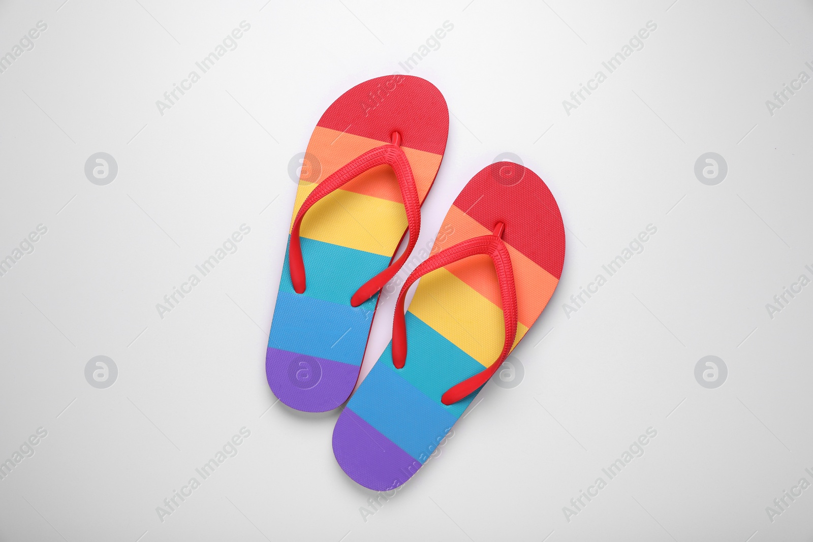 Photo of Stylish rainbow flip flops on white background, top view