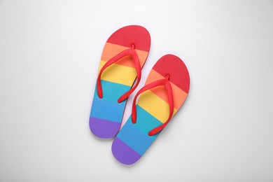 Photo of Stylish rainbow flip flops on white background, top view
