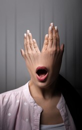 Hallucinations. Shocked woman with mouth on hands instead of head on light grey background